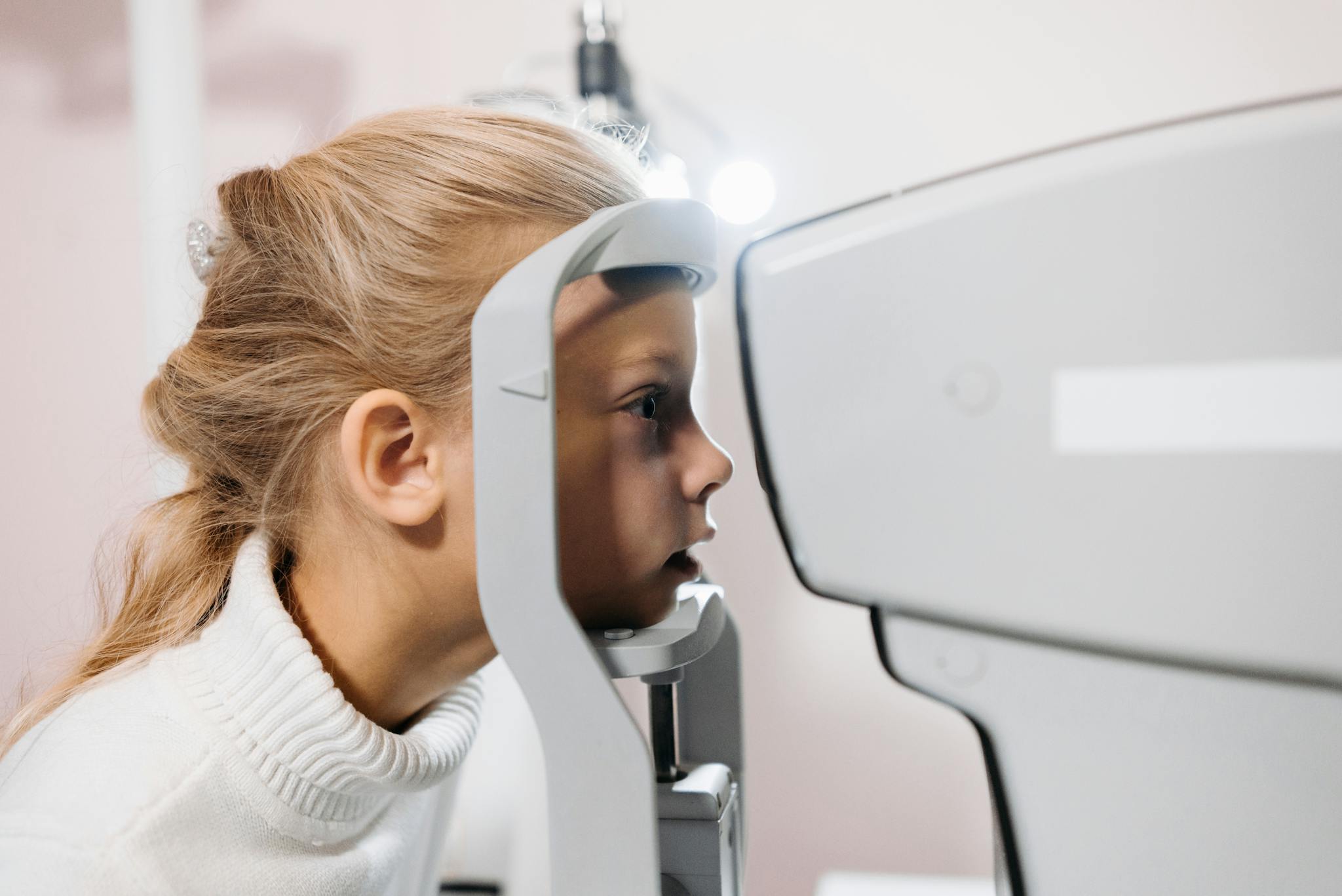 A young girl getting her vision tested using optometry equipment at a clinic.